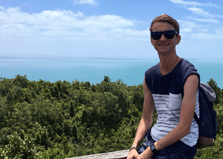 Nederlandse jongen poseert voor de zee vanaf de vulkaan op Rangitoto Island in Auckland